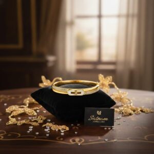 Gold-plated bracelet with imitation diamonds displayed on a black velvet cushion.